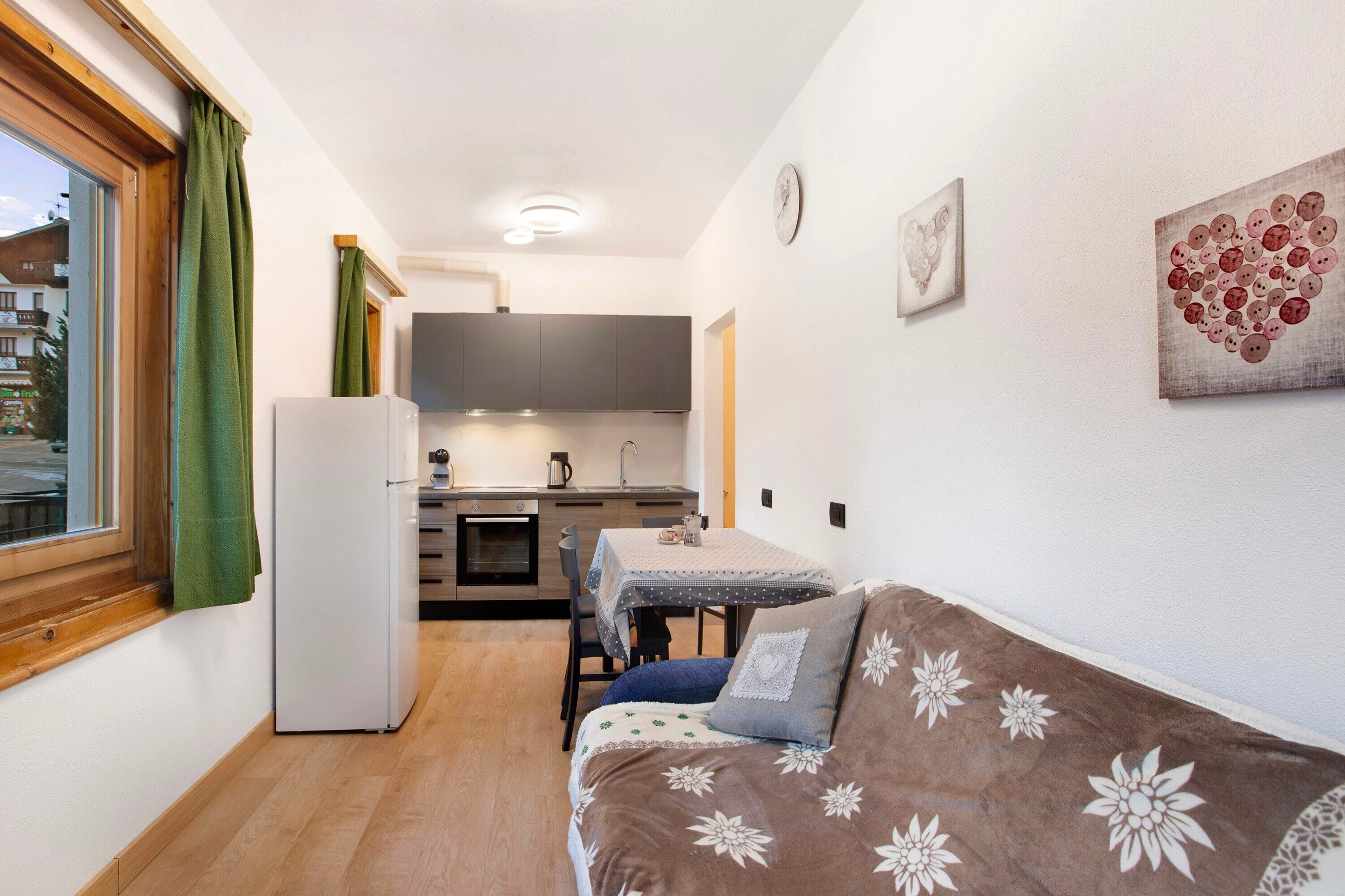 A compact living space with a kitchenette, a dining area, and a sofa with floral upholstery.