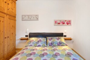 A bedroom with a bed, wooden wardrobe, and two wall-mounted light fixtures. - Apartment "Arlecchino" with Mountain View, Balcony & Wi-Fi (Livigno)