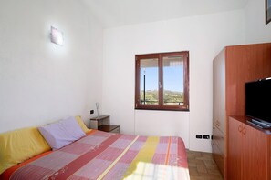 Une chambre à coucher comprenant un lit, une télévision, une armoire, une fenêtre et une table de chevet.