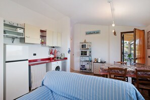 Un espacio habitable compacto con kitchenette, comedor y cama.
