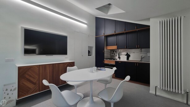 Une cuisine moderne avec des meubles de couleur sombre, un plan de travail blanc et un four encastré.