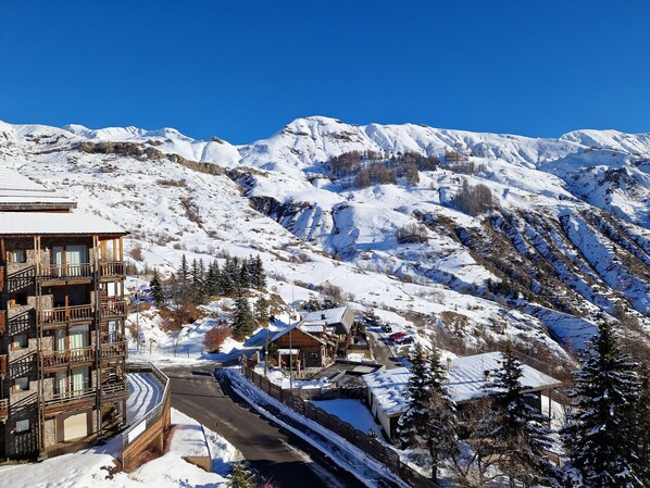 A snow-covered mountain landscape with a multi-story building featuring balconies and a ski lift in the background.