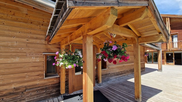 Ein Holzhaus mit überdachter Veranda und hängenden Blumenkörben.