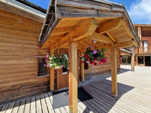 A wooden building with a covered porch and hanging flower baskets.