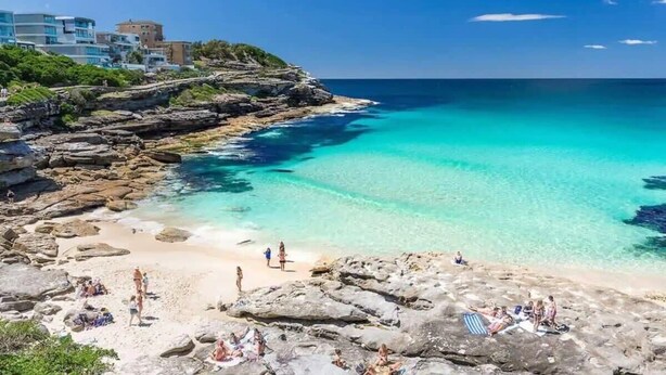 Una spiaggia costiera con terreno roccioso e acque turchesi cristalline.