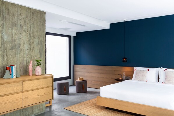 A modern bedroom with a wooden bed, a concrete accent wall, and a large window.