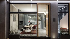 A modern interior with a dining area, a staircase, and a view into a kitchen.