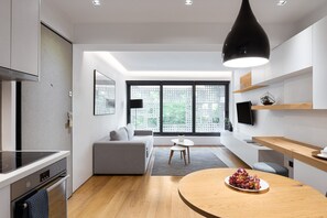 A modern kitchen with a built-in oven, a dining area with a round wooden table, and a gray sofa. - Cozy Living, Urban Stripes Athens (Athens)