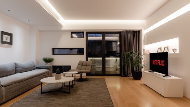 A modern living room with a grey sofa, a coffee table, a TV, and a sliding glass door leading to a balcony. - Family Maisonette, Urban Stripes Athens (Athens)