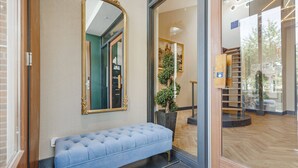 Un área de recepción con un banco, un espejo y una planta en maceta.