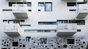 En moderne bygning med flere balkoner og en mønstret facade.