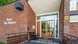 L’entrée d’un bâtiment en briques, avec une enseigne indiquant « Bens The Walton » et le numéro « 90 » sur le mur.