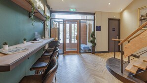 Un espace d’accueil avec un comptoir en bois, des sièges et un escalier.