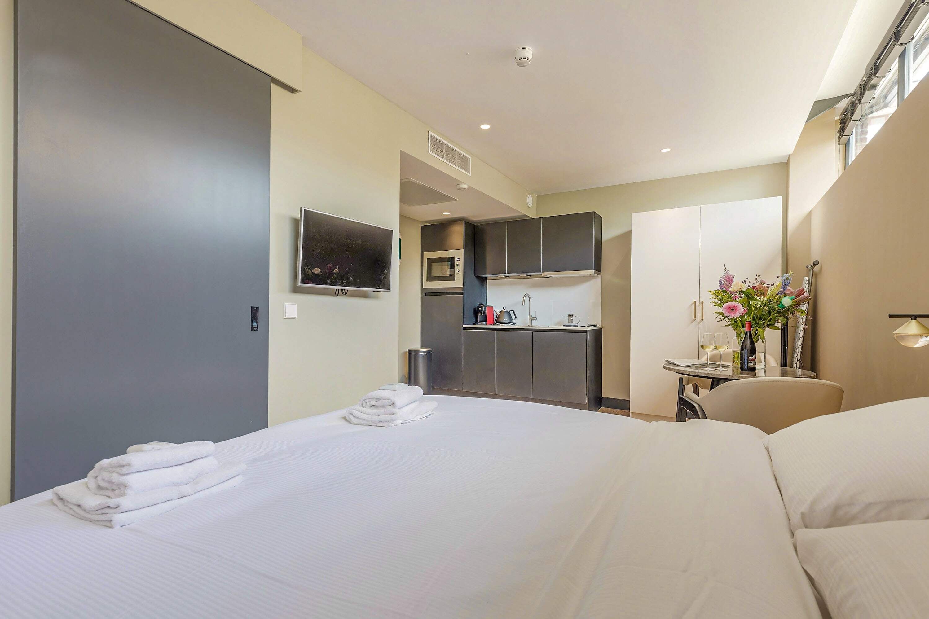 Hotelkamer met een bed, een klein keukenblok, een televisie en een eethoek met een tafel en stoelen.