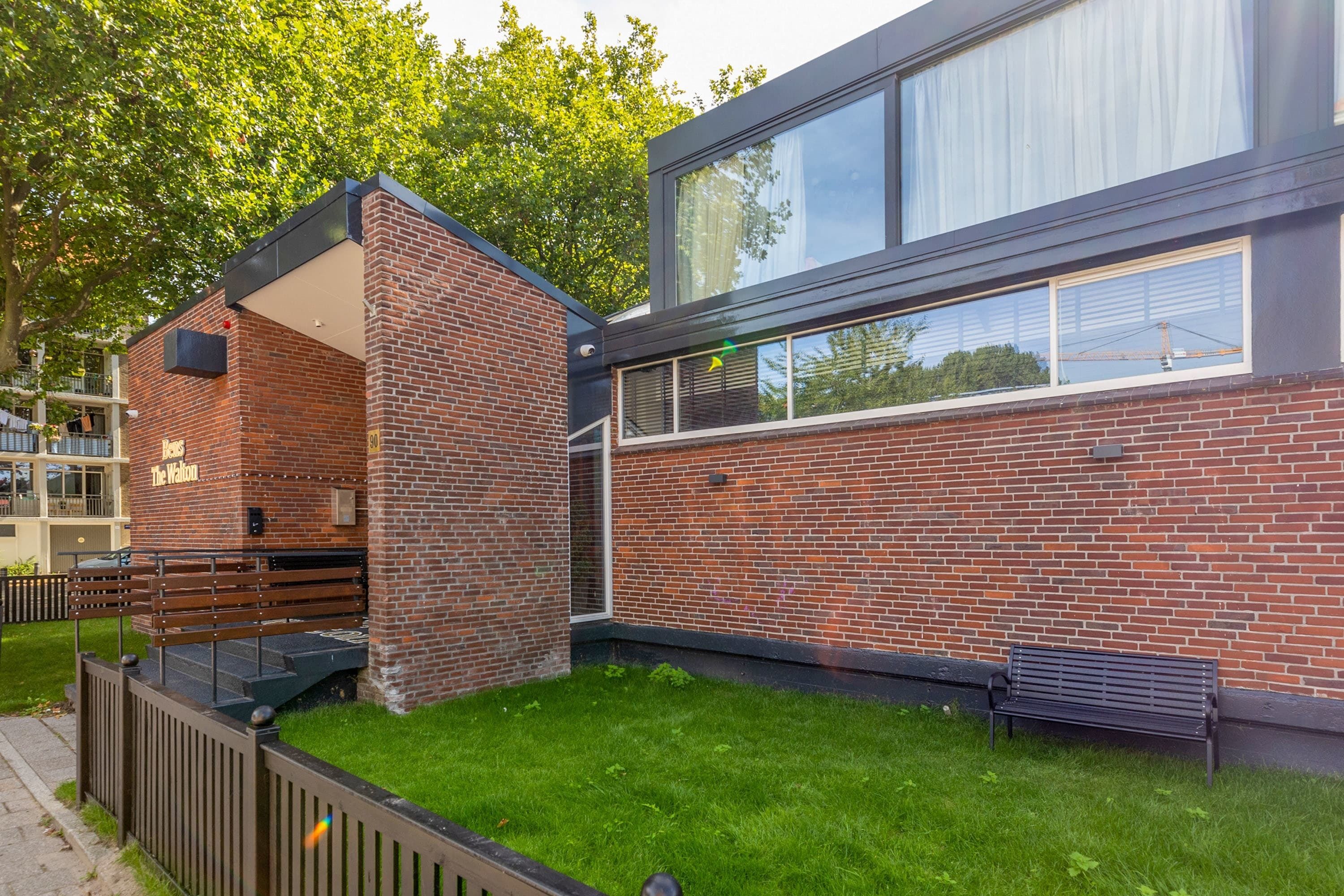 Een modern gebouw met een bakstenen gevel, grote ramen en een gazon.