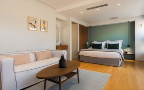 A modern bedroom with a white sofa, a wooden coffee table, a bed with green pillows, and two framed pictures on the wall. - Acropolis Suite II, Urban Stripes Athens (Athens)