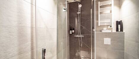 Un baño moderno con ducha envuelta en vidrio, inodoro y barra para toallas.