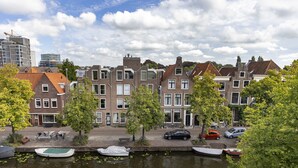 A canal with boats, a row of traditional houses, and a modern building in the background. - Breathe Boutique hotel Leiden (Leiden)