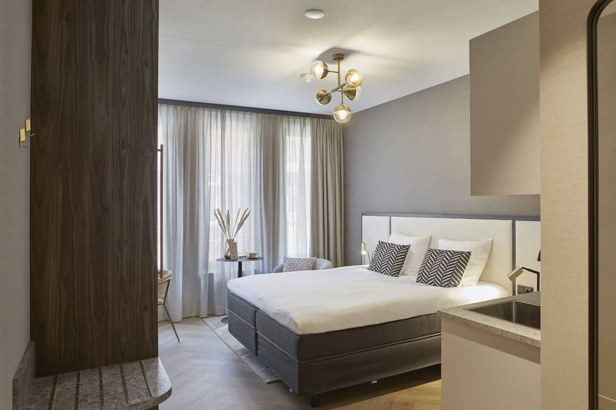 A modern bedroom with a large bed, bedside table, and a built-in sink.