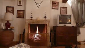Una sala de estar acogedora con chimenea, un televisor sobre un mueble de madera y cuadros en las paredes.