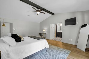 Een moderne hotelkamer met een bed, een bureau, een televisie en een kledingkast.