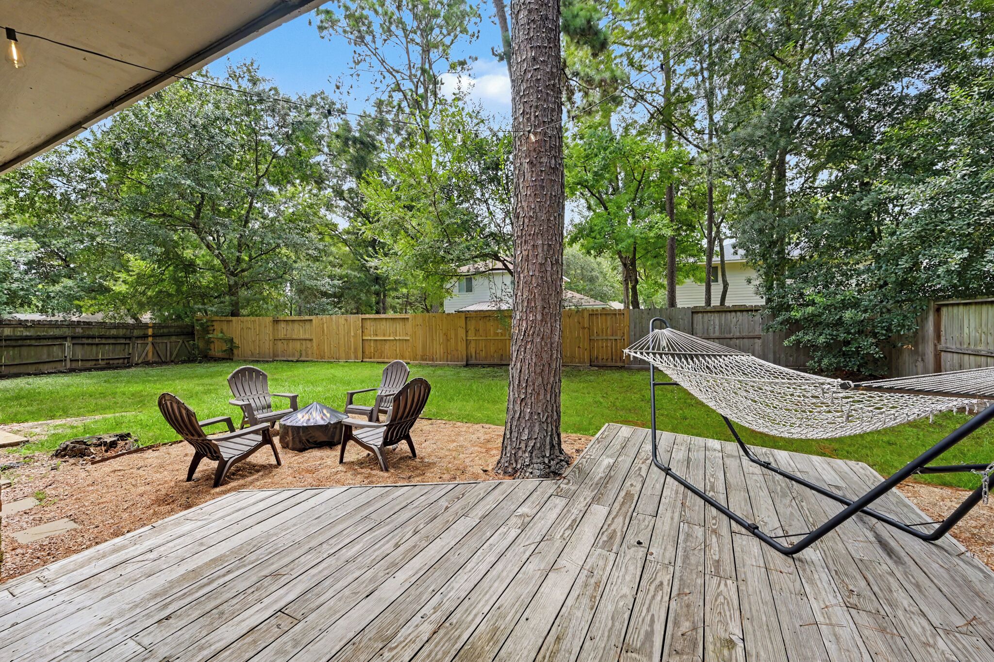 A wooden deck with outdoor furniture and a hammock.