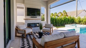Un espacio al aire libre moderno con chimenea, asientos y piscina.