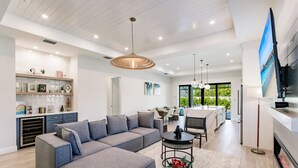 A modern living room with a grey sectional sofa, a coffee table, and a fireplace. - Luxe Coastal Getaway Naples Vanderbilt Beach Home Heated Pool/Spa (Naples)