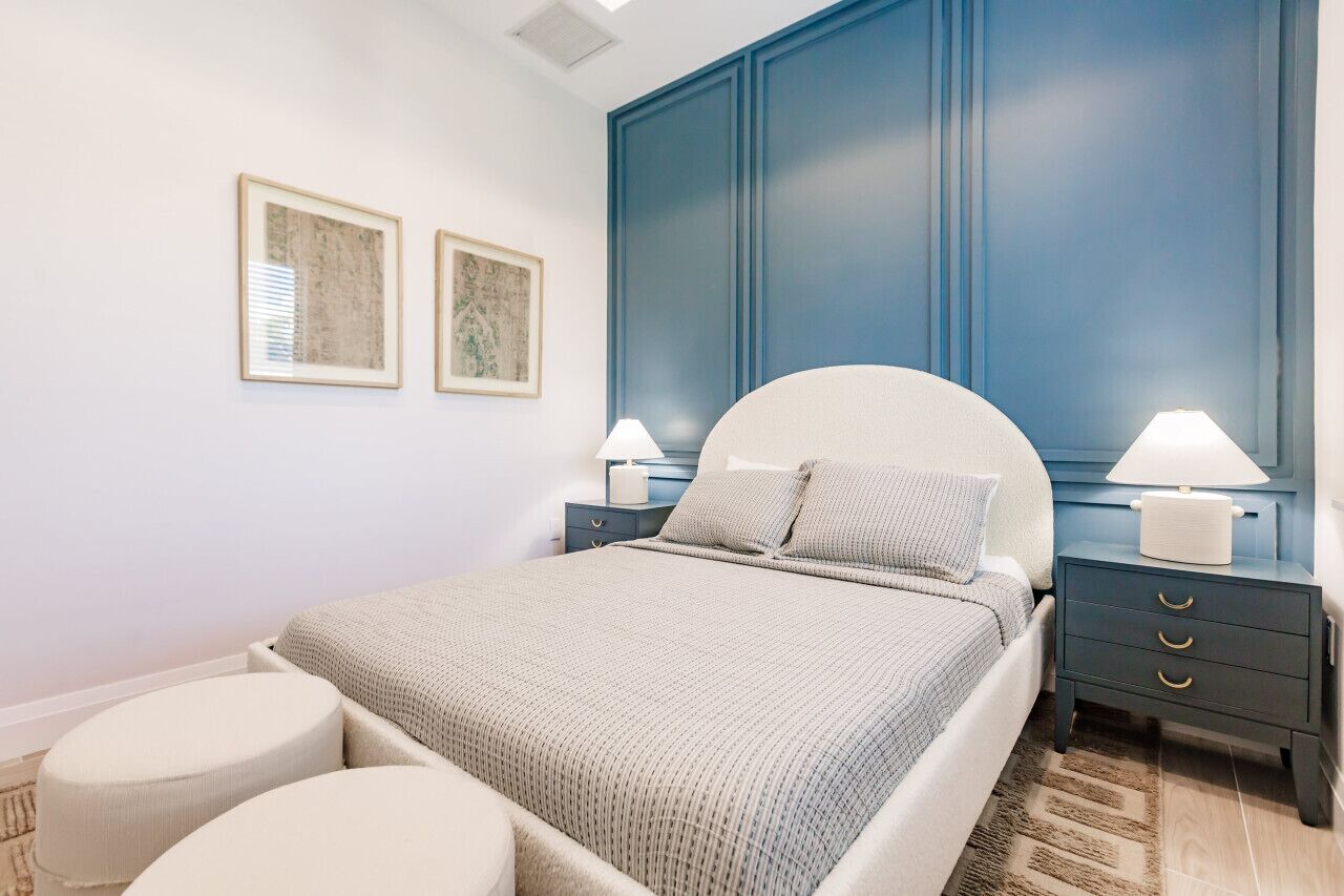 Un dormitorio moderno con una cama grande, dos mesitas de noche con lámparas y dos cuadros enmarcados en la pared.