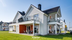 Uma casa de dois andares com varanda, alpendre e chaminé visível.
