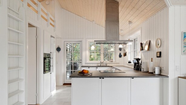 A modern kitchen with white cabinetry, a large island, and a view of greenery outside. - Awesome home in Græsted with WiFi (Græsted)