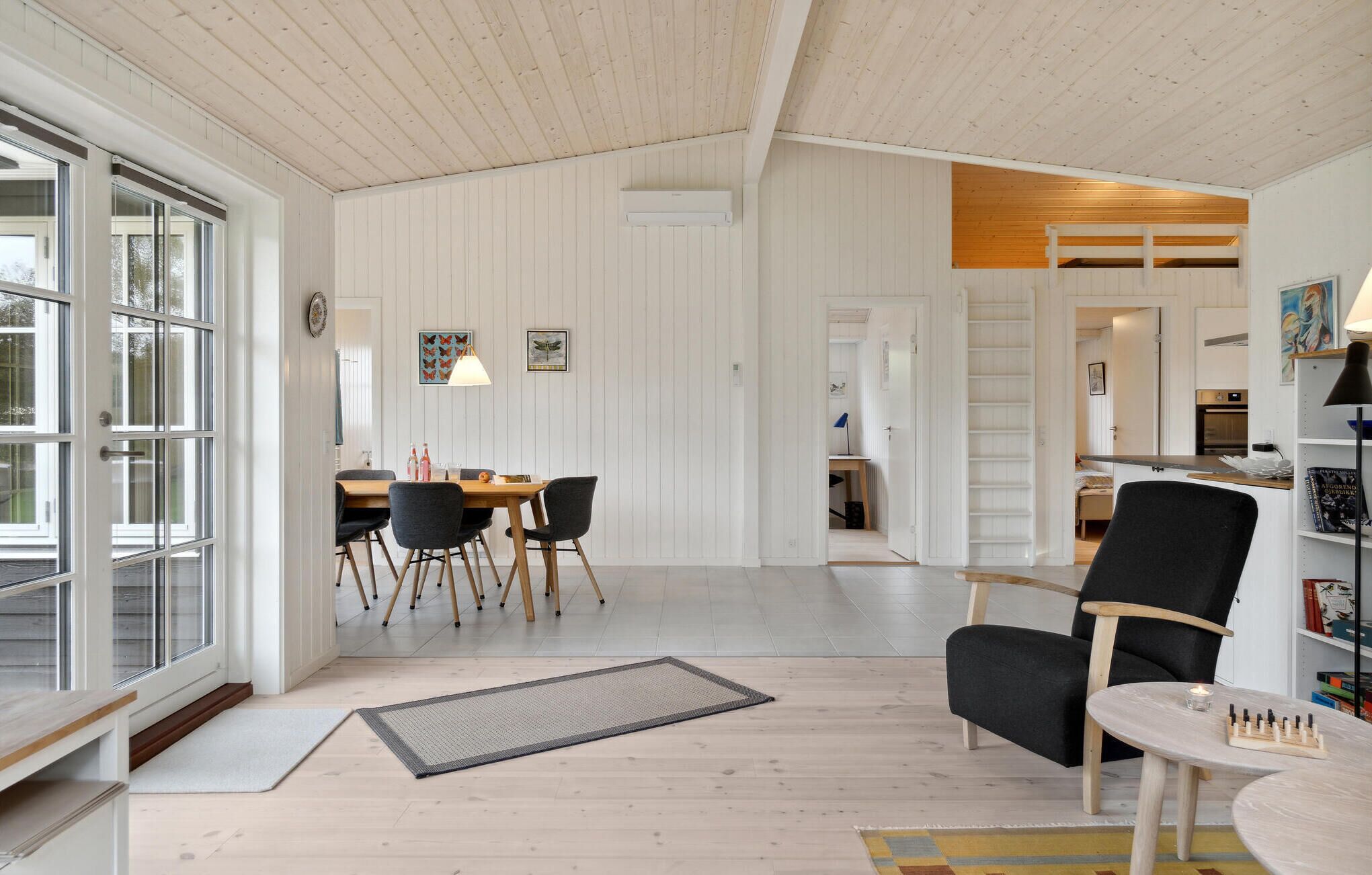 A spacious room with a dining area, a black armchair, and a small table with candles.