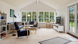 A spacious living room with a high ceiling, large windows, a blue sofa, a wooden desk, and a bookshelf. - Awesome home in Græsted with WiFi (Græsted)