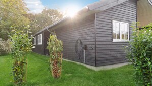 A modern wooden cabin with a well-maintained lawn and a hose attached to the exterior wall. - Awesome home in Græsted with WiFi (Græsted)