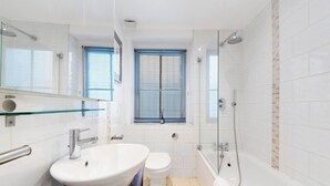 Un baño moderno con cabina de ducha de vidrio, lavamanos blanco y retrete.