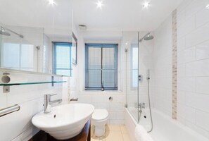 A modern bathroom with a glass shower enclosure, a white sink, and a toilet.