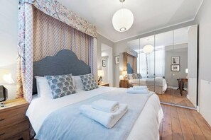 Une chambre moderne avec un grand lit, un miroir et un plancher en bois.
