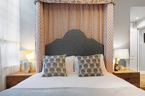 Ein Bett mit Kopfteil, zwei Kissen und ein Nachttisch mit Lampe.