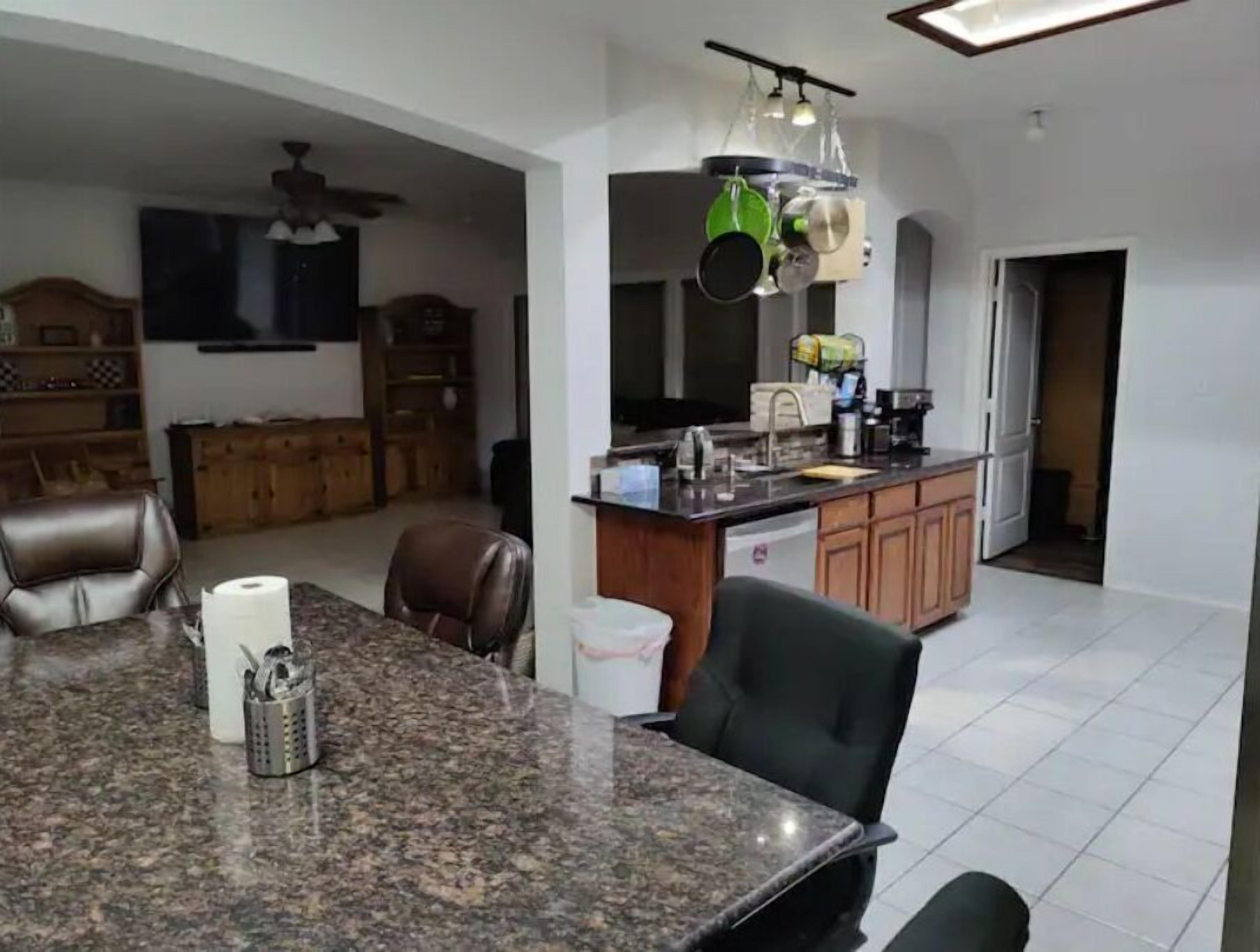 A kitchen with granite countertops, a dining area with a table and chairs, and a ceiling fan.