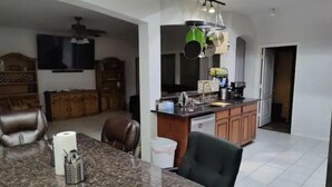 A kitchen with granite countertops, a dining area with a table and chairs, and a ceiling fan. - Texas Motor Speedway Comfort Zone (Justin)