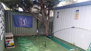 A backyard with artificial turf, a putting green, and a wooden play structure. - SizzlingSummerRates@TheWhiteHouse (Carrum Downs)