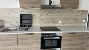 A modern kitchen with wooden cabinetry, a stainless steel sink, a built-in dishwasher, and an oven.