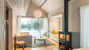 A cozy cabin interior with a wooden interior, a sofa, a coffee table, and a wood-burning stove. - 3 bedroom amazing home in Tuddal (Tuddal)