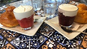 Uma mesa com duas travessas de doces e dois copos de sobremesa.