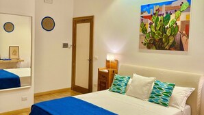 Quarto com cama grande, mesa de cabeceira com abajur, quadro na parede e porta.