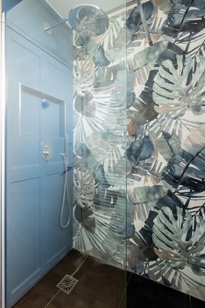 A bathroom with a glass shower enclosure, a blue door, and a leaf-patterned wall. - Parkside Innovation, by Veeve (Paris)