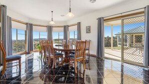 Un espace repas avec une table ronde et des chaises, de grandes fenêtres et une vue sur l’extérieur.