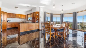 Une cuisine moderne avec des meubles en bois, un grand îlot central et un coin repas offrant une vue agréable.