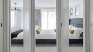 Hotellihuone, jossa on sänky, yöpöytä, lamppu ja ikkuna, jossa on verhot.