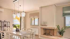 Un comedor con una mesa y sillas, una chimenea, una estantería y vistas al exterior.